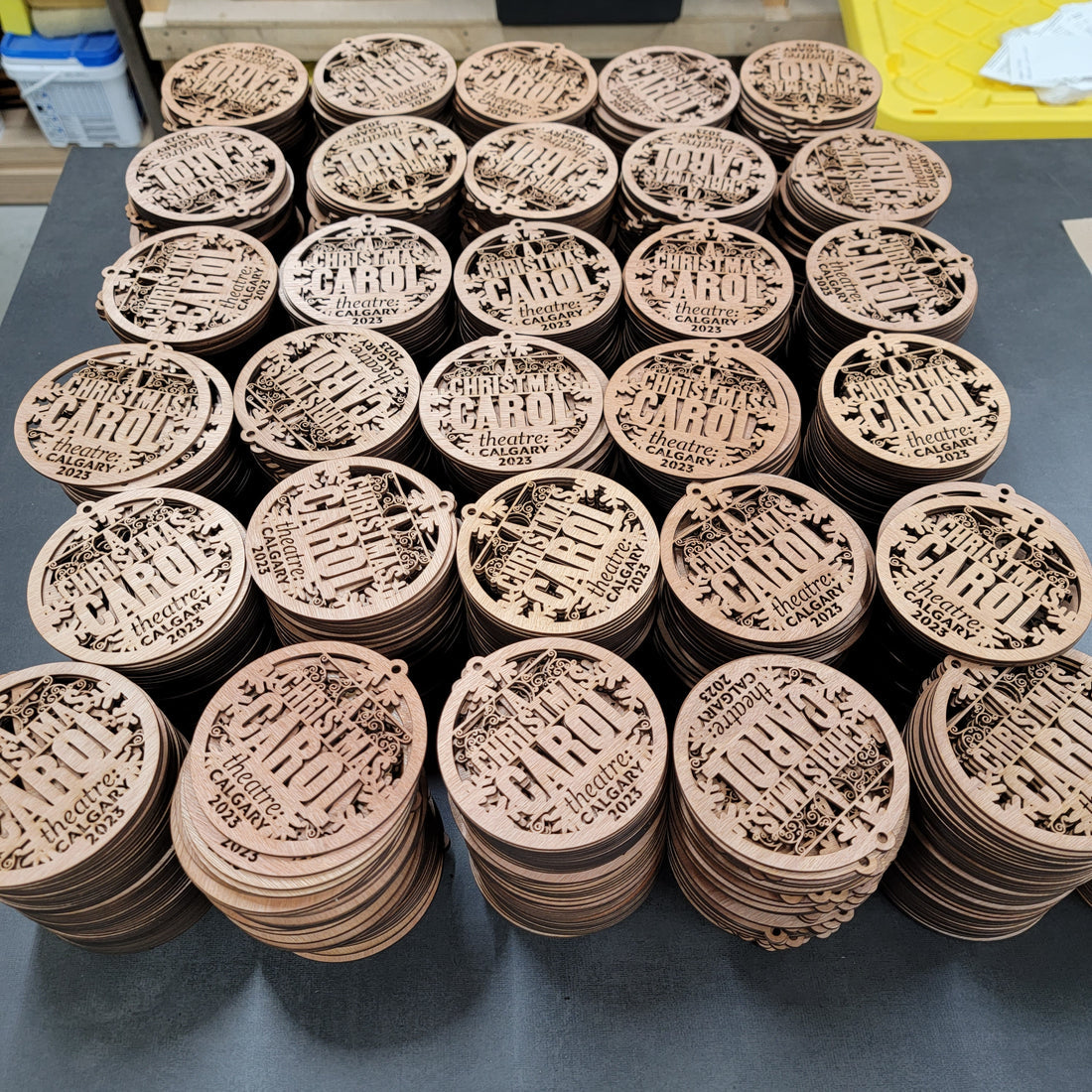 Group of laser-cut custom wooden ornaments with A Christmas Carol Theatre Calgary logo – bulk corporate order | Ornemoi